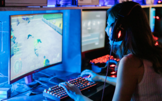 Photo of a young woman sitting in front of a computer screen playing a game.