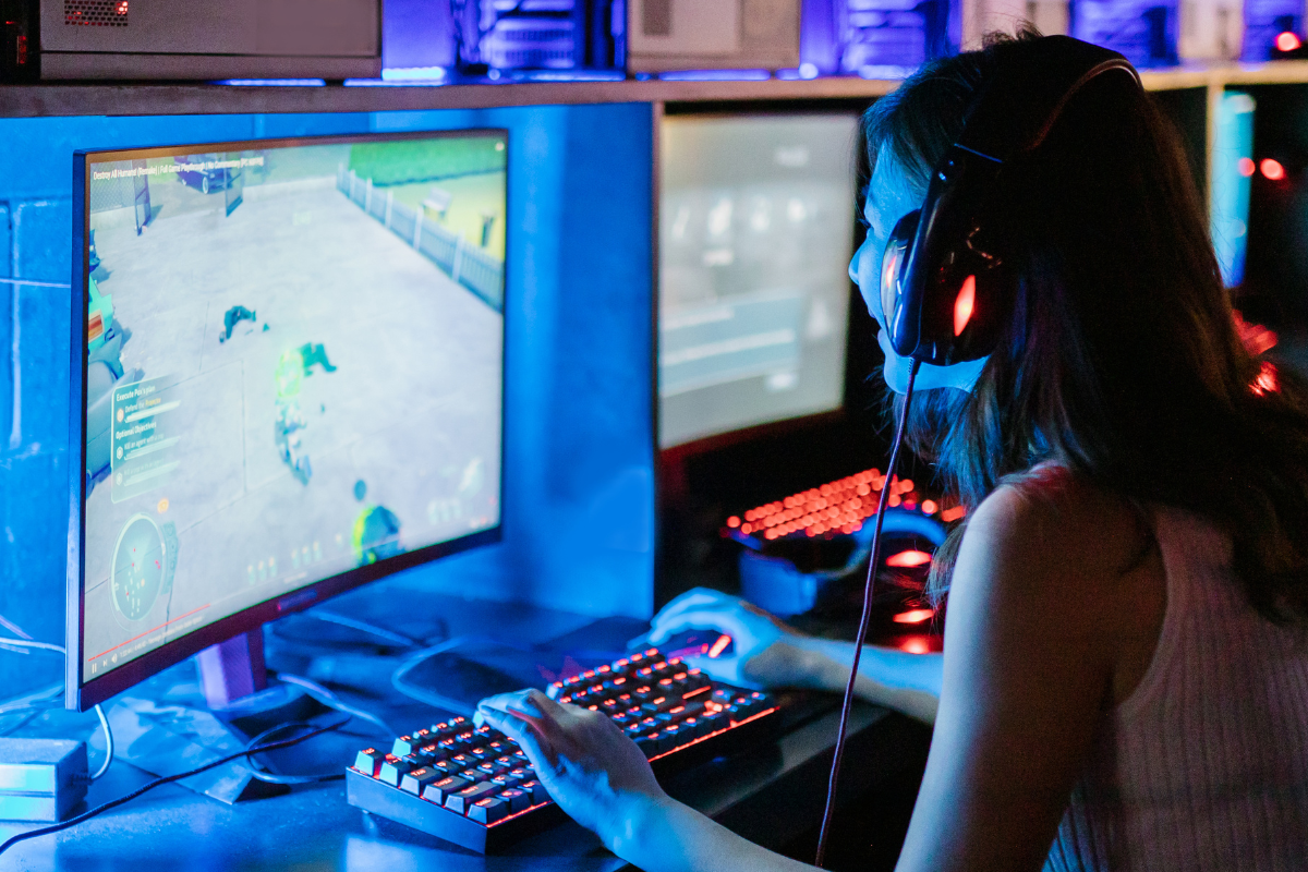 Photo of a young woman sitting in front of a computer screen playing a game.