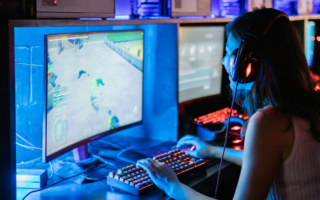 Photo of a young woman sitting in front of a computer screen playing a game.