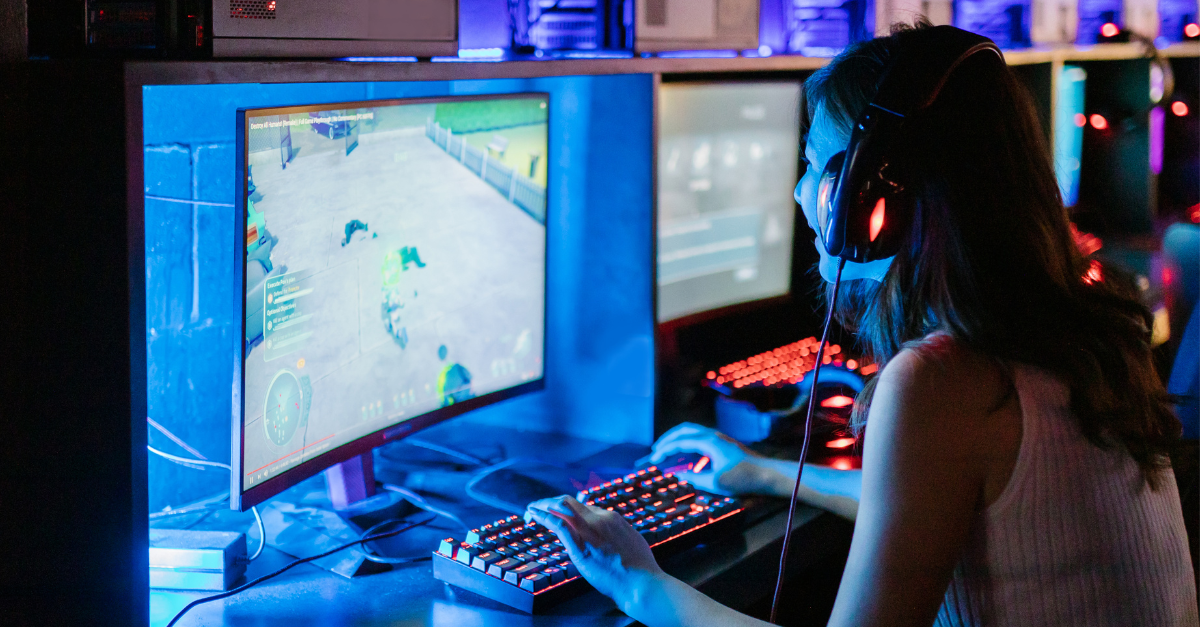 Photo of a young woman sitting in front of a computer screen playing a game.